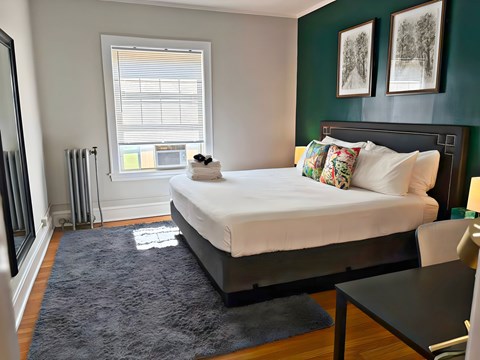 A bedroom with a large bed and a window with blinds.