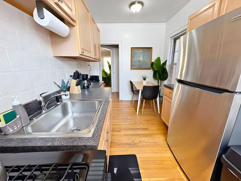 A modern kitchen with a stainless steel refrigerator and a dining area with a table and chairs.