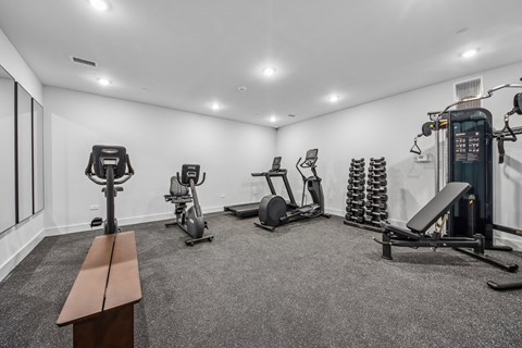 A gym with a bench, weights, and exercise equipment.