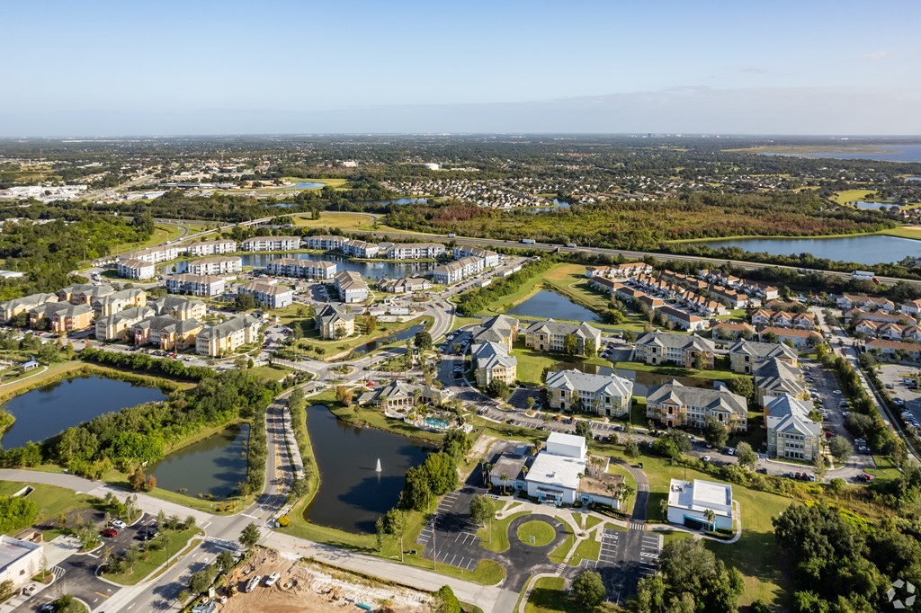 A bird's eye view of a residential area with a lake and a road.