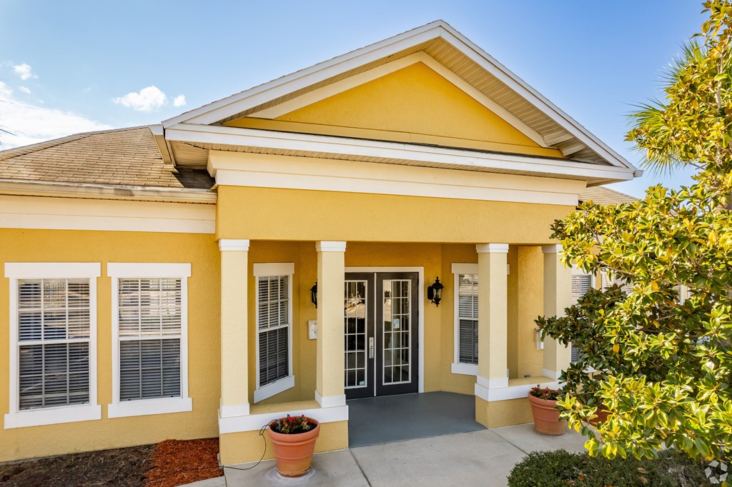A yellow house with a brown roof and a glass door.
