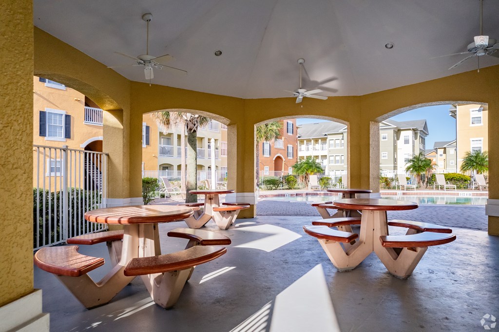 A patio with tables and chairs and a ceiling fan.