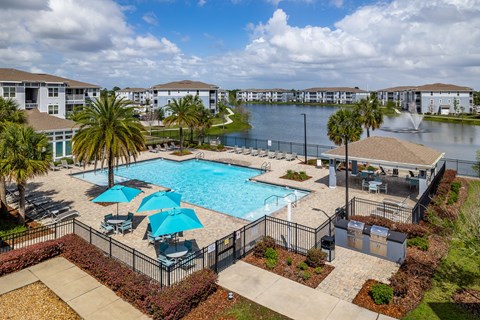 A pool surrounded by a black fence with blue umbrellas.