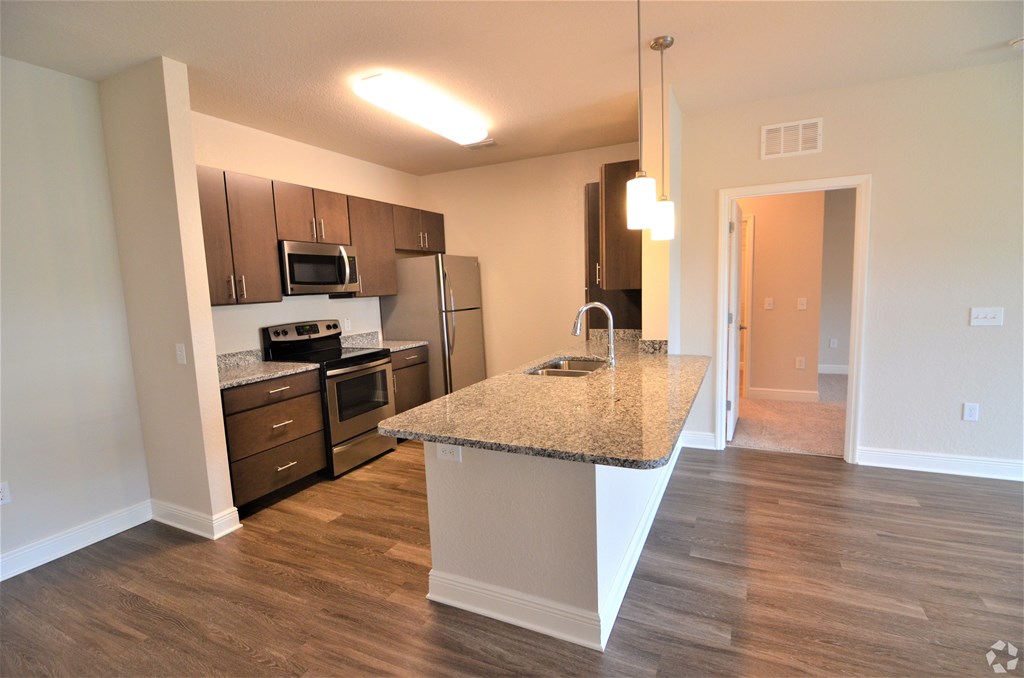 A kitchen with a granite countertop and stainless steel appliances.