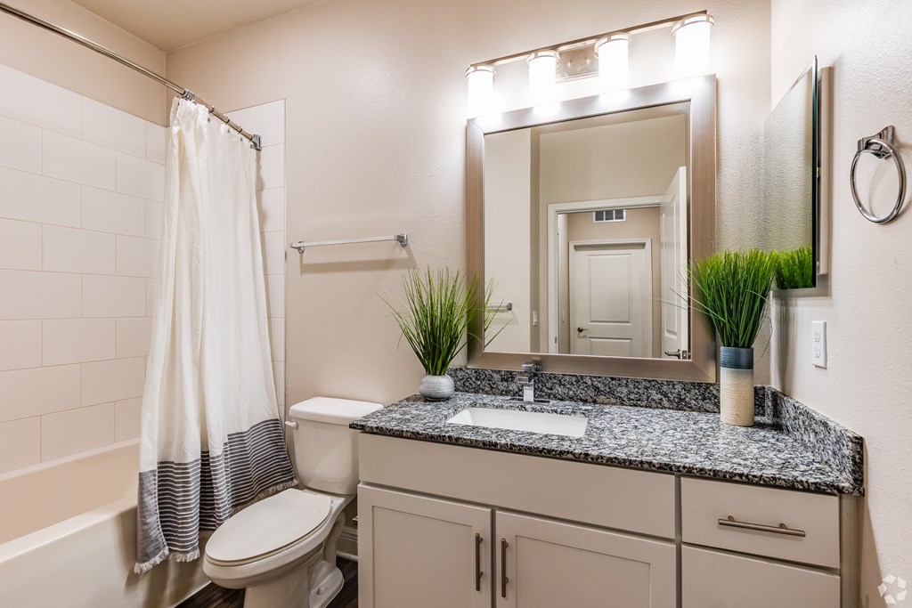 A bathroom with a toilet, sink, and mirror.