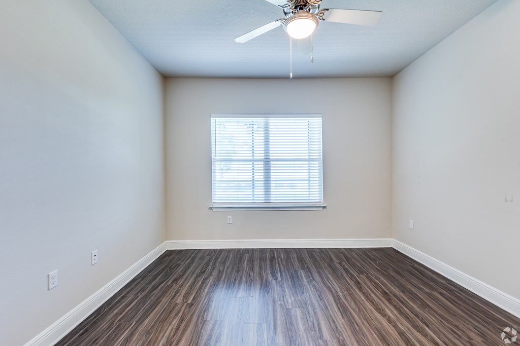 A room with a ceiling fan and wooden flooring.