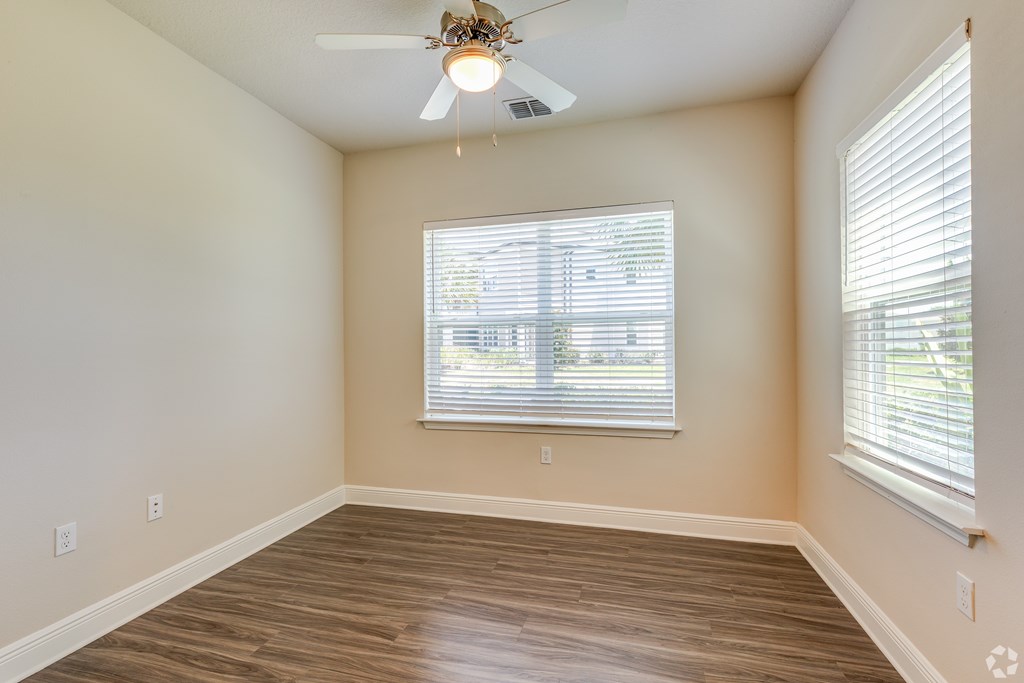 A room with a ceiling fan and a window with blinds.