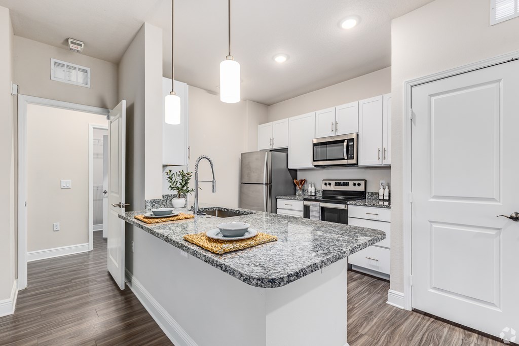 A kitchen with a granite countertop and white cabinets.