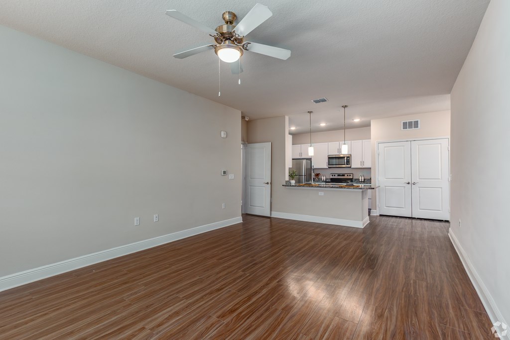 A room with a ceiling fan and wooden flooring.