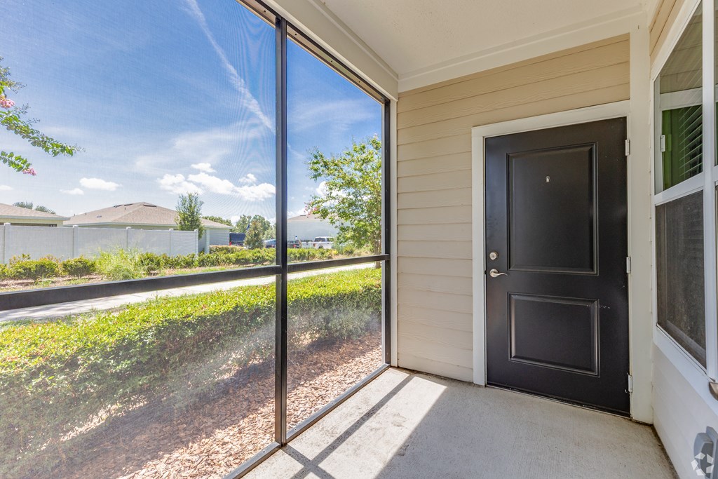 A black door is on the right side of a screened-in porch.