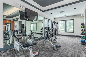 A gym with a variety of equipment including treadmills, weights, and exercise machines.