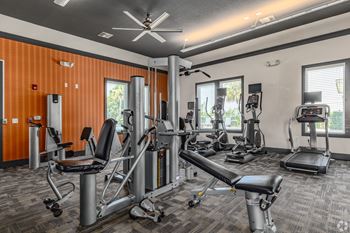 A gym with orange walls and various exercise equipment.