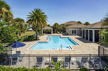A pool surrounded by a black fence and chairs.