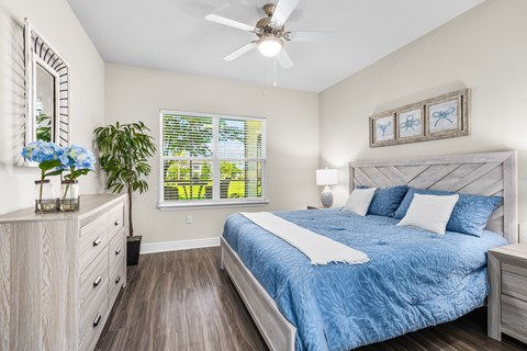 A bedroom with a bed, dresser, and window.