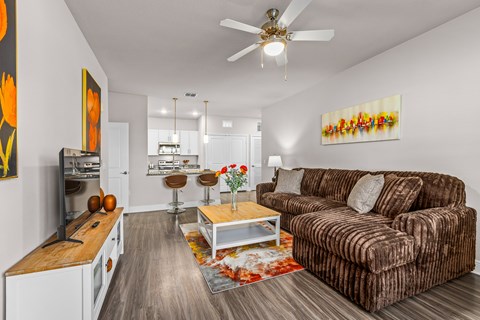 A living room with a brown couch and a ceiling fan.