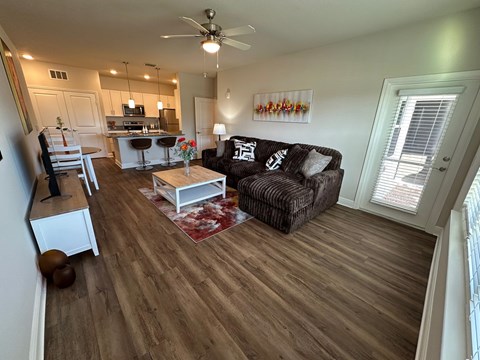 A living room with a brown couch and a wooden floor.