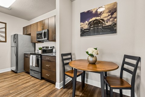 A kitchen with a table and chairs and a fridge.