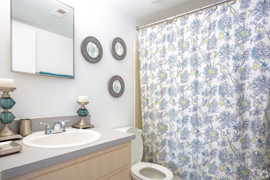 A bathroom with a floral shower curtain and a white toilet.