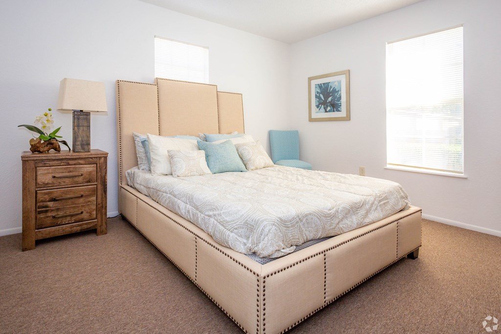 A bedroom with a large bed, a wooden nightstand, and a window.