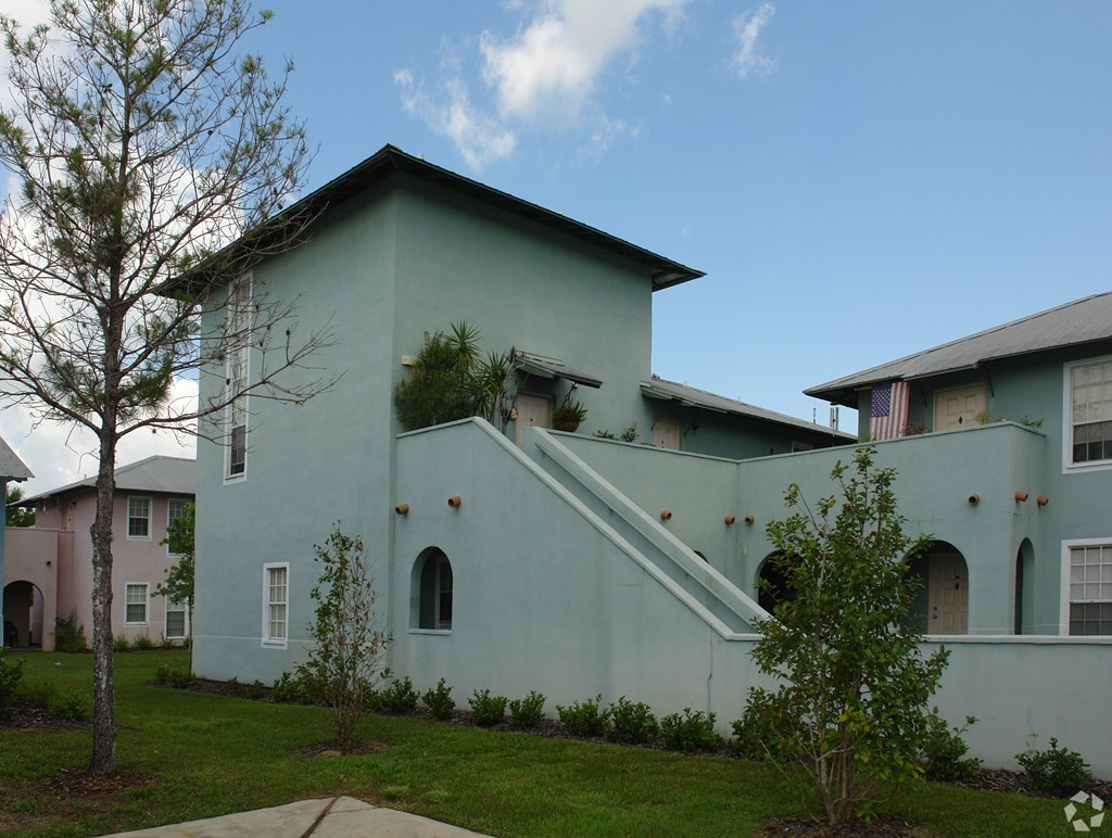 A green house with a tree in front.