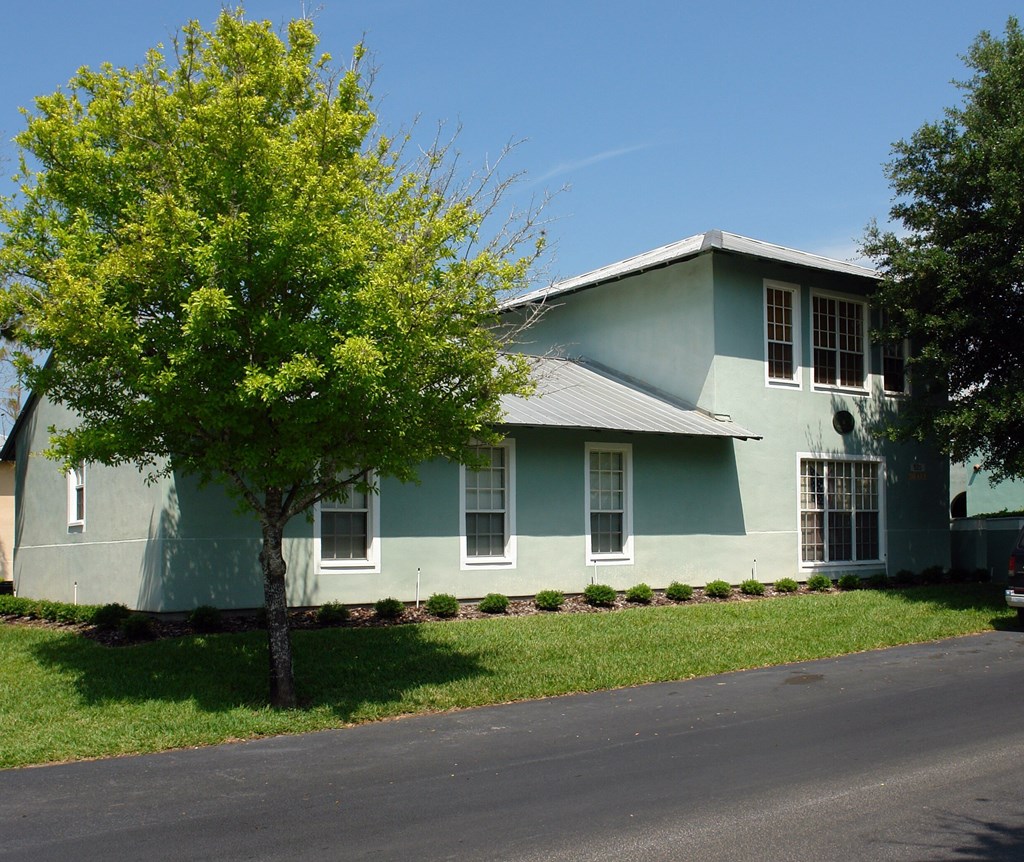 A green house with a tree in front of it.