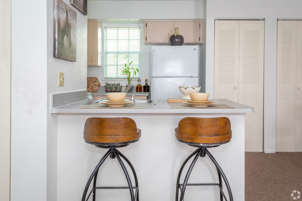 A kitchen with a white countertop and two bar stools.