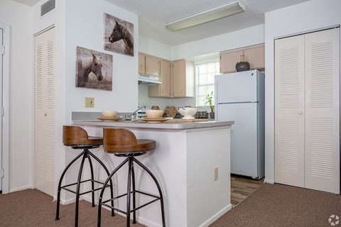 A kitchen with a white counter and brown bar stools.