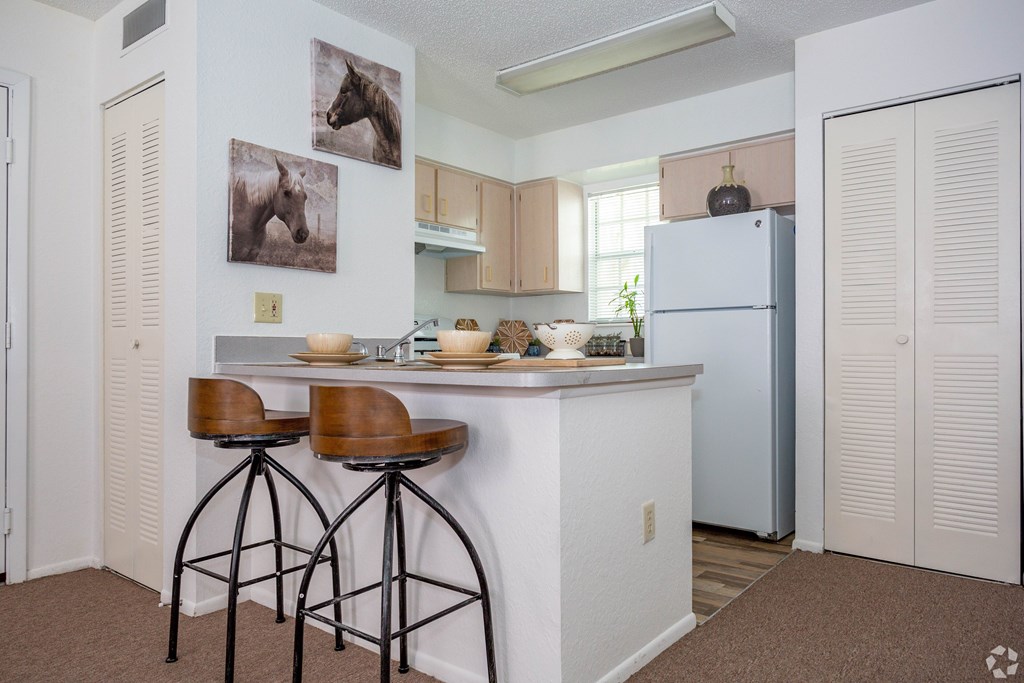 A kitchen with a white counter and brown bar stools.