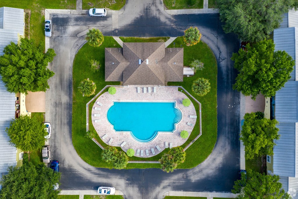 A bird's eye view of a residential area with a swimming pool and houses.