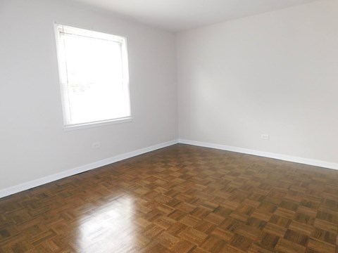 A room with a wooden floor and a window letting in light.