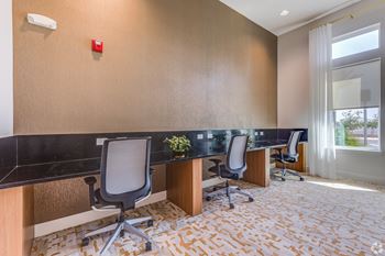 A room with a desk and chairs and a red alarm button on the wall.