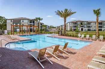 A pool surrounded by chairs and palm trees.