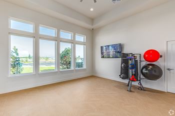 A room with a large window, a TV, and exercise equipment.