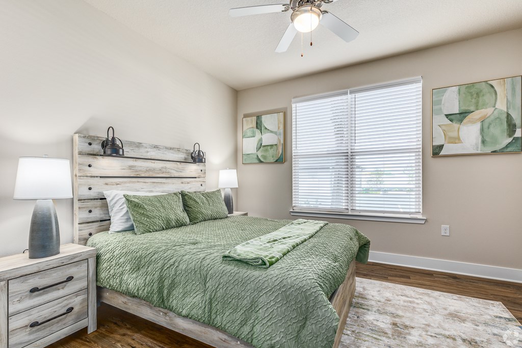 A bedroom with a bed, nightstand, and a ceiling fan.