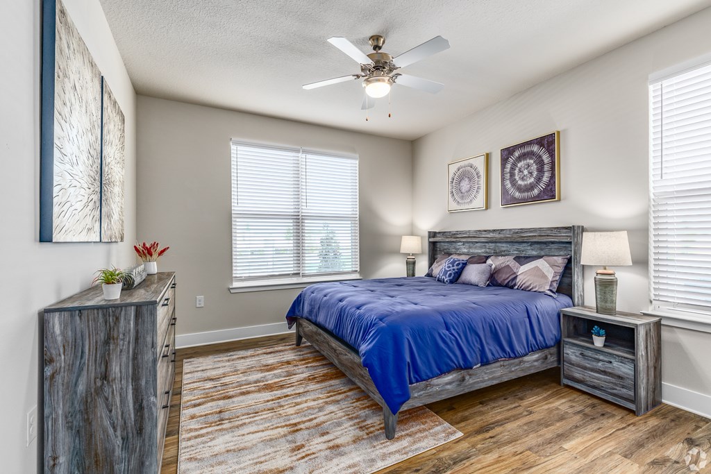 A bedroom with a bed, nightstand, and a ceiling fan.