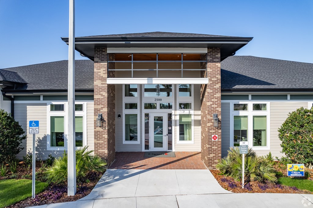 The image shows a building entrance with a clear blue sky in the background.