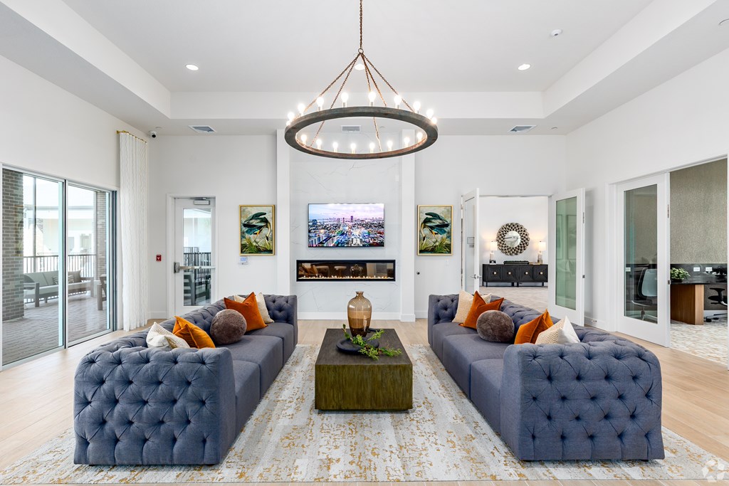 A living room with a large blue couch and a chandelier hanging from the ceiling.