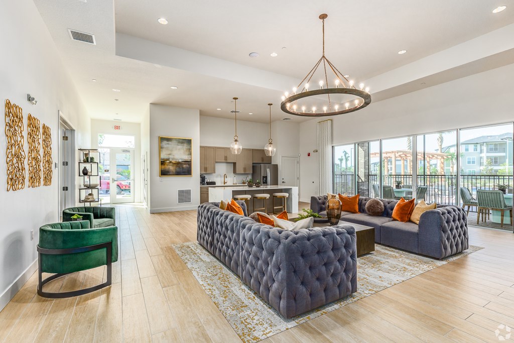 A modern living room with a green sofa and a grey tufted ottoman.
