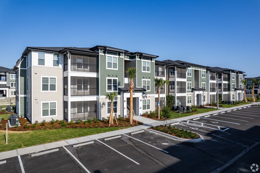 Apartment complex with a parking lot in front.