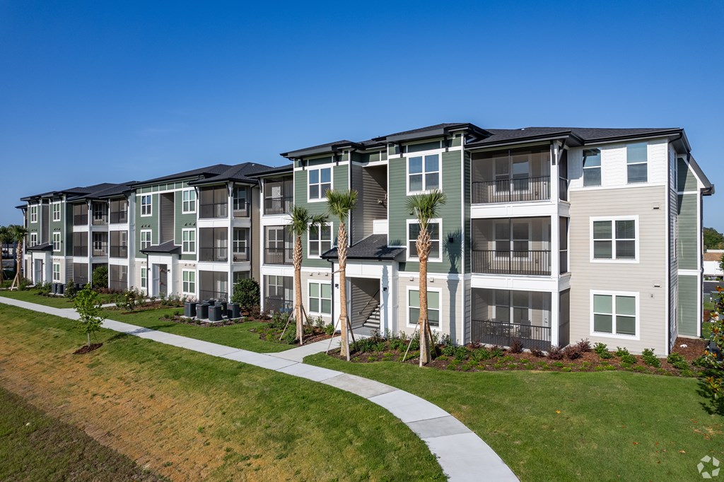 A modern apartment building with a well-maintained lawn and walkway.