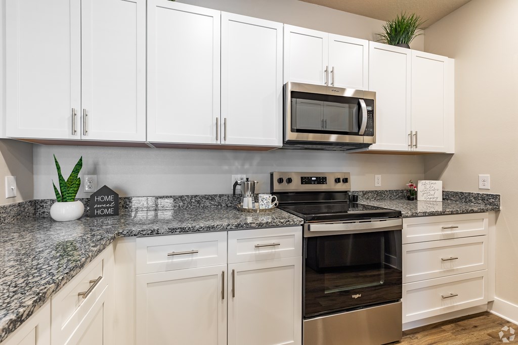 A kitchen with white cabinets and a granite countertop.