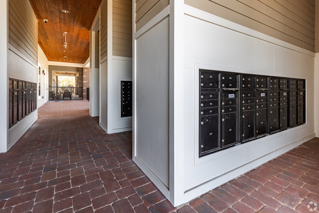 A long hallway with a brick floor and a wall of mailboxes.