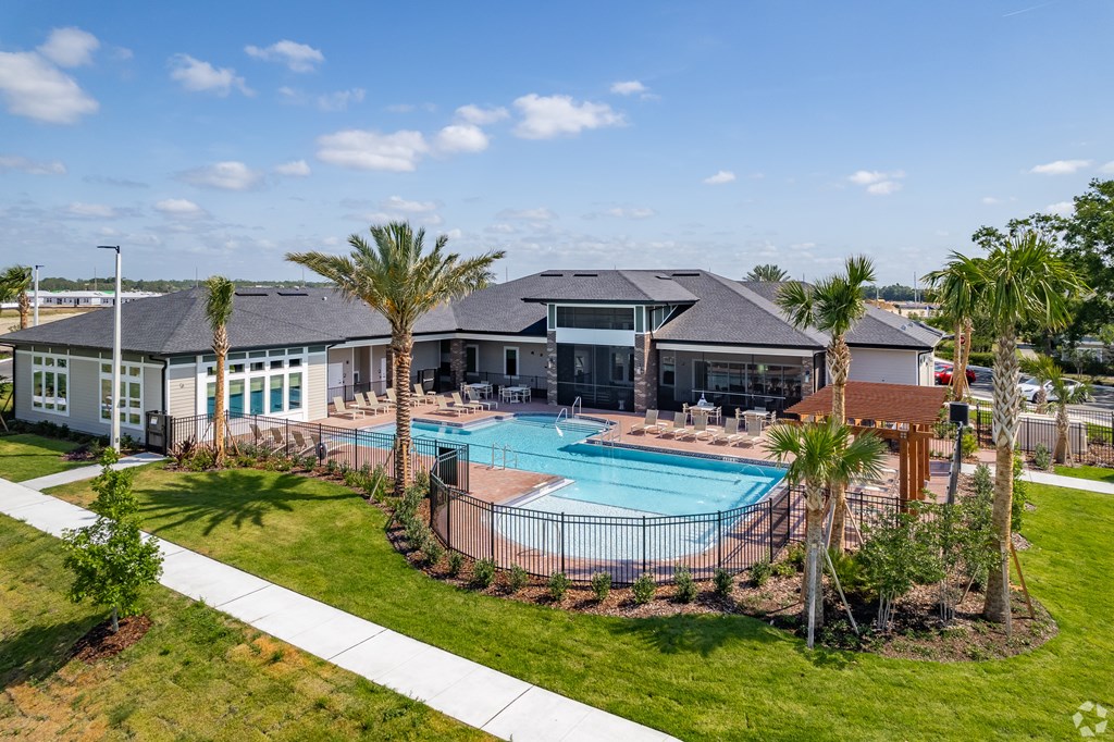 A swimming pool surrounded by palm trees and a building in the background.