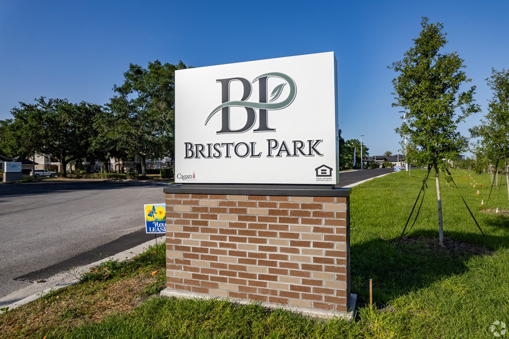 A sign for Bristol Park stands in front of a grassy area.