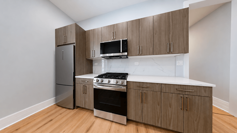 A kitchen with wooden cabinets and a stainless steel refrigerator.