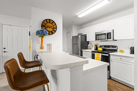 A kitchen with a white island and brown chairs.