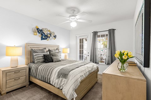 A bedroom with a bed, nightstand, and a vase of flowers.