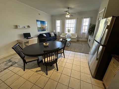 A black table with four chairs is in the middle of a kitchen and dining room.