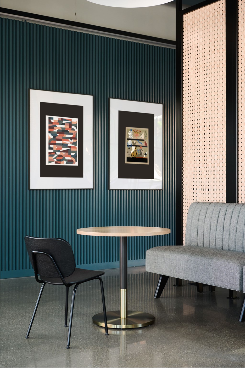 A black chair sits in front of a table with a grey couch behind it.