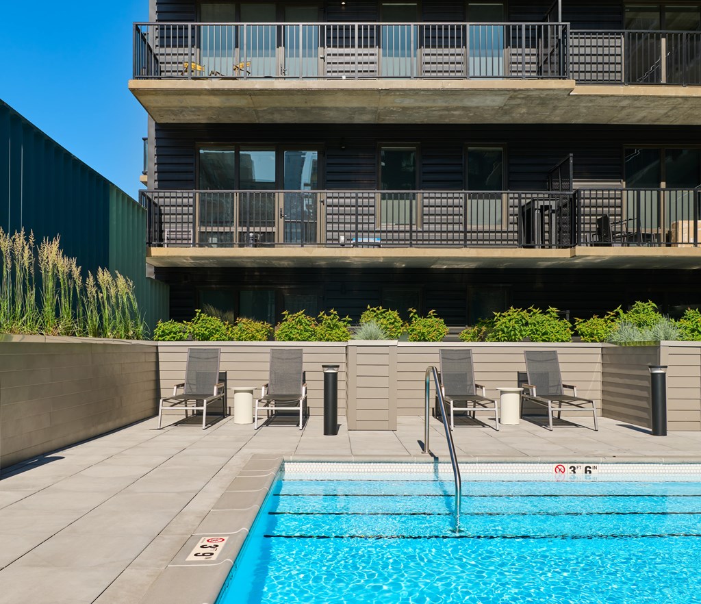 A swimming pool in front of a building with a balcony.